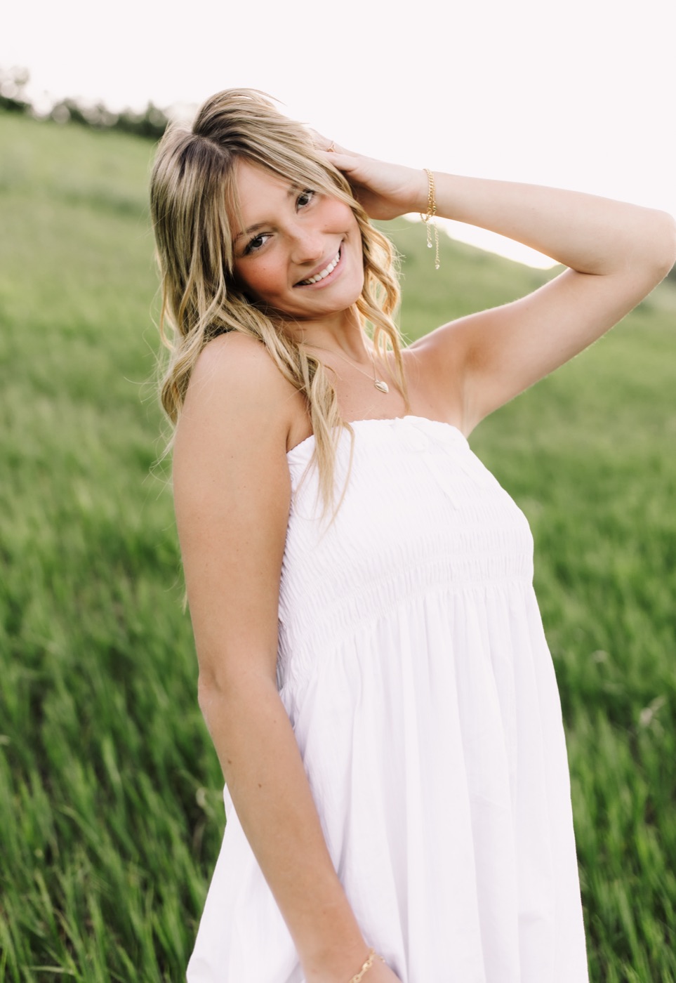 Harper smiling in a white dress in a green field
